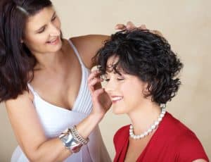 Happy woman in her 40s styling short hair curls on her friend